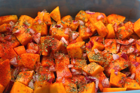 Sheet pan with pieces of butternut squash, onion, herbs and spices. Preparing pumpkin for a roast. Selective focus.の写真素材