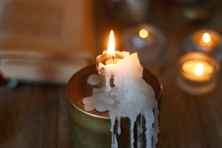 Books, lit candles, red wine, snacks and various decoration on the table. Dark academia or Halloween concept. Selective focus.の写真素材