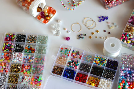 Hand figurine, colorful friendship bracelets, necklaces, various beads and DIY supplies on the table. Making jewelry at home. Selective focus.の写真素材