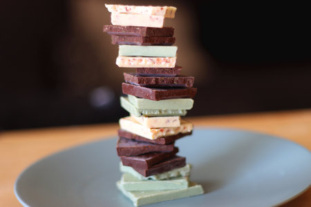 Pile of various chocolate pieces on a plate. Dark, white and matcha chocolate. Selective focus.の写真素材