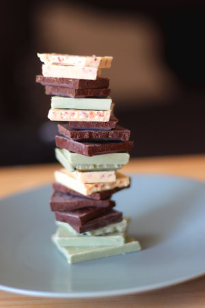 Pile of various chocolate pieces on a plate. Dark, white and matcha chocolate. Selective focus.の写真素材