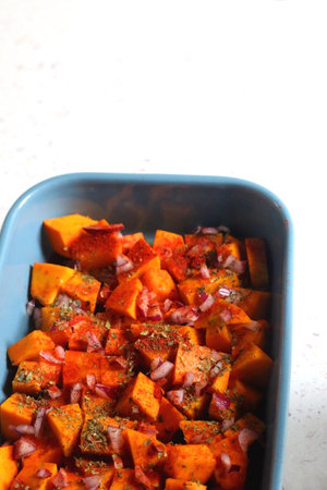 Sheet pan with pieces of butternut squash, onion, herbs and spices. Selective focus.の写真素材