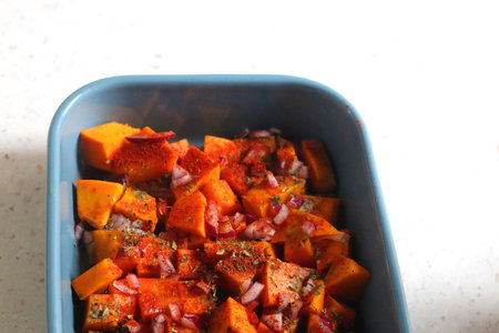 Sheet pan with pieces of butternut squash, onion, herbs and spices. Preparing pumpkin for a roast. Selective focus.の写真素材
