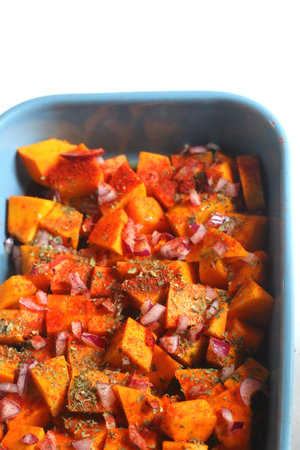Sheet pan with pieces of butternut squash, onion, herbs and spices. Preparing pumpkin for a roast. Selective focus.の写真素材