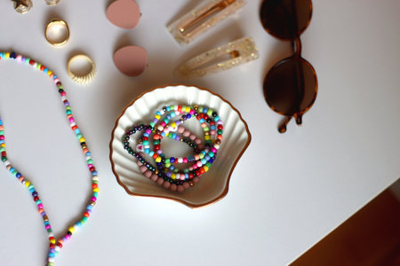 Hand figurine, eyewear, gold jewelry, colorful bead jewelry, statement rings and various hair accessories on the white table. Selective focus.の写真素材