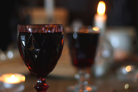 Books, lit candles, red wine, snacks and various decoration on the table. Dark academia or Halloween concept. Selective focus.の写真素材