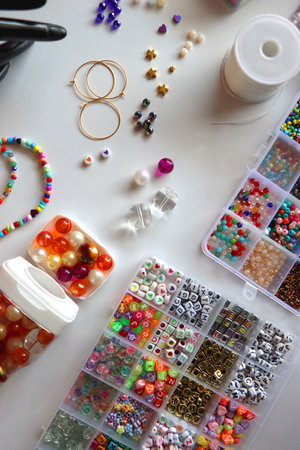 Hand figurine, colorful friendship bracelets, necklaces, various beads and DIY supplies on the table. Making jewelry at home. Flat lay.の写真素材