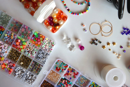 Hand figurine, colorful friendship bracelets, necklaces, various beads and DIY supplies on the table. Making jewelry at home. Flat lay.の写真素材