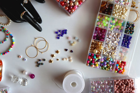 Hand figurine, colorful friendship bracelets, necklaces, various beads and DIY supplies on the table. Making jewelry at home. Flat lay.の写真素材