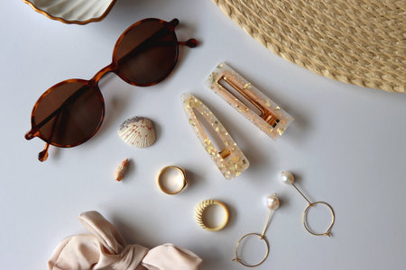 Sunglasses, straw hat, shells and jewelry in neutral colors. Seasonal summer accessories on white background. Flat lay.の写真素材