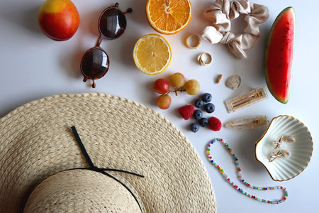 Straw hat, sunglasses, seasonal fruit, seashells and colorful accessories on white backgrounds. Cute summer essentials. Flat lay.の写真素材
