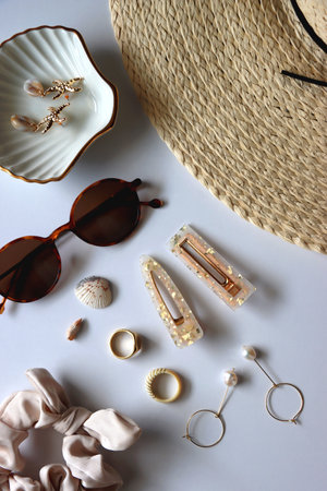 Sunglasses, straw hat, shells and jewelry in neutral colors. Seasonal summer accessories on white background. Flat lay.の写真素材
