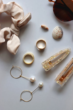 Sunglasses, straw hat, shells and jewelry in neutral colors. Seasonal summer accessories on white background. Flat lay.の写真素材