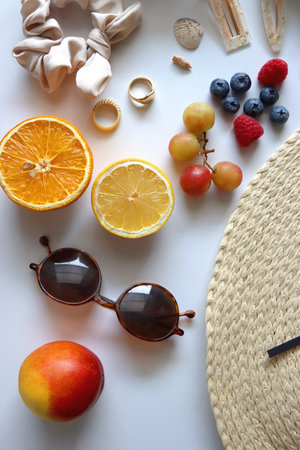 Straw hat, sunglasses, seasonal fruit, seashells and colorful accessories on white backgrounds. Cute summer essentials. Flat lay.の写真素材