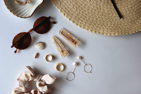 Sunglasses, straw hat, shells and jewelry in neutral colors. Seasonal summer accessories on white background. Flat lay.の写真素材