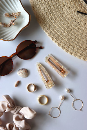 Sunglasses, straw hat, shells and jewelry in neutral colors. Seasonal summer accessories on white background. Flat lay.の写真素材