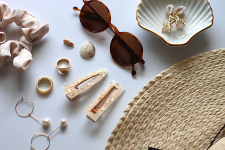 Sunglasses, straw hat, shells and jewelry in neutral colors. Seasonal summer accessories on white background. Selective focus.の写真素材