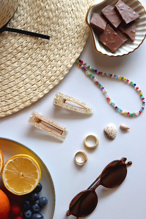 Straw hat, sunglasses, fresh fruit, chocolate and accessories. Summer essentials on the table. Top view.の写真素材