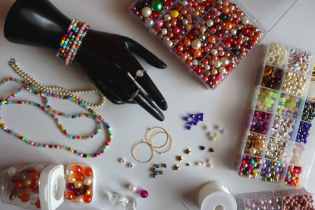 Hand figurine, colorful friendship bracelets, necklaces, various beads and DIY supplies on the table. Making jewelry at home. Flat lay.の写真素材