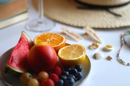 Glass of cocktail, straw hat, sunglasses, books, fresh fruit, chocolate and accessories. Summer essentials on the table. Selective focus.の写真素材