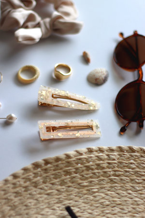 Sunglasses, straw hat, shells and jewelry in neutral colors. Seasonal summer accessories on white background. Selective focus.の写真素材