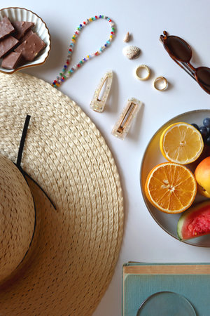 Straw hat, sunglasses, fresh fruit, chocolate and accessories. Summer essentials on the table. Top view.の写真素材
