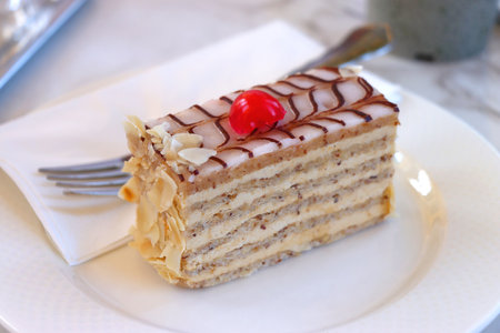 Slice of layered almond cake, served on the table. Selective focus.の写真素材