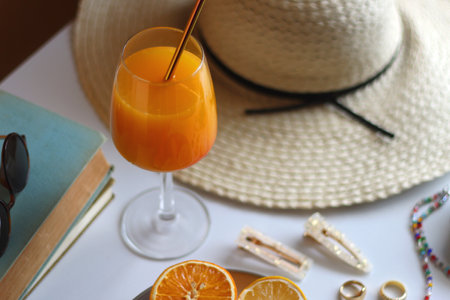 Glass of cocktail, straw hat, sunglasses, books, fresh fruit, chocolate and accessories. Summer essentials on the table. Selective focus.の写真素材