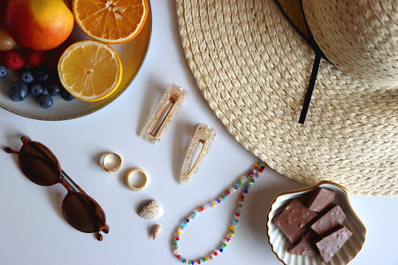 Straw hat, sunglasses, fresh fruit, chocolate and accessories. Summer essentials on the table. Top view.の写真素材