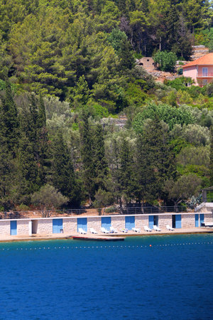 Beautiful beach with blue and white changing cabins, in Vela Luka, small town on island Korcula, Croatia.の写真素材