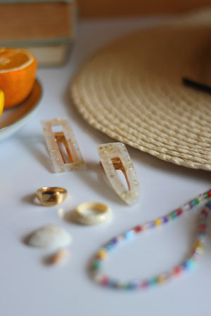 Hair clips, straw hat, fresh fruit, chocolate and accessories. Summer essentials on the table. Selective focus.の写真素材