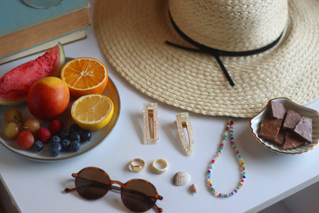 Glass of cocktail, straw hat, sunglasses, books, fresh fruit, chocolate and accessories. Summer essentials on the table. Selective focus.の写真素材