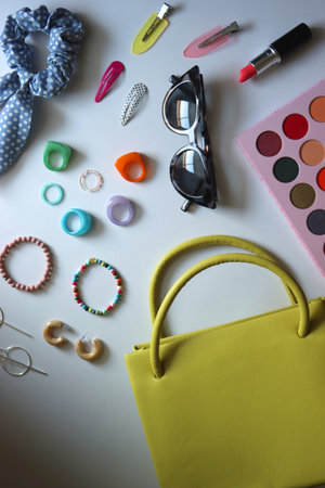 Green bag, various colorful jewelry, sunglasses, hair accessories and colorful make up on white background. Flat lay.の写真素材