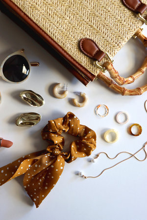 Wicker purse, sunglasses, scrunchie, lipstick and various gold and neutral jewelry on white background. Top view.の写真素材