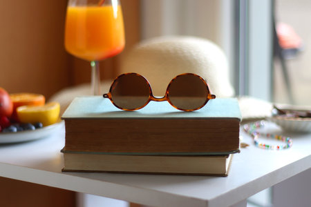 Glass of cocktail, straw hat, sunglasses, books, fresh fruit, chocolate and accessories. Summer essentials on the table. Selective focus.の写真素材