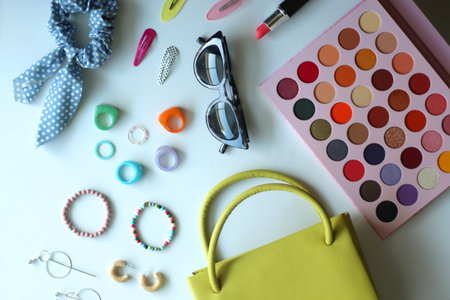 Green bag, various colorful jewelry, sunglasses, hair accessories and colorful make up on white background. Flat lay.の写真素材