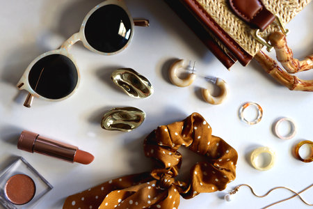 Wicker purse, sunglasses, scrunchie, lipstick and various gold and neutral jewelry on white background. Top view.の写真素材