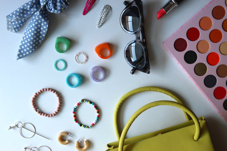 Green bag, various colorful jewelry, sunglasses, hair accessories and colorful make up on white background. Flat lay.の写真素材