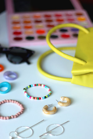 Green bag, various colorful jewelry, sunglasses, hair accessories and colorful make up on white background. Selective focus.の写真素材