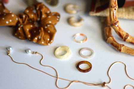 Wicker purse, sunglasses, scrunchie, lipstick and various gold and neutral jewelry on white background. Selective focus.の写真素材