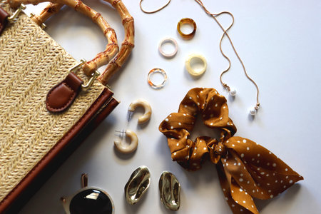 Wicker purse, sunglasses, scrunchie, lipstick and various gold and neutral jewelry on white background. Top view.の写真素材