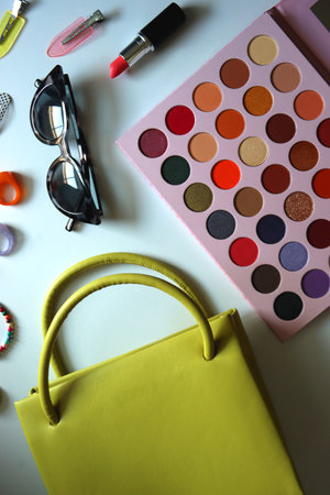 Green bag, various colorful jewelry, sunglasses, hair accessories and colorful make up on white background. Flat lay.の写真素材