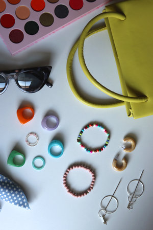 Green bag, various colorful jewelry, sunglasses, hair accessories and colorful make up on white...