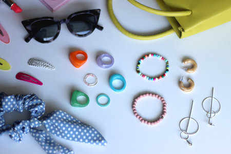 Various colorful jewelry, sunglasses, hair accessories and colorful make up on white background. Selective focus.の写真素材