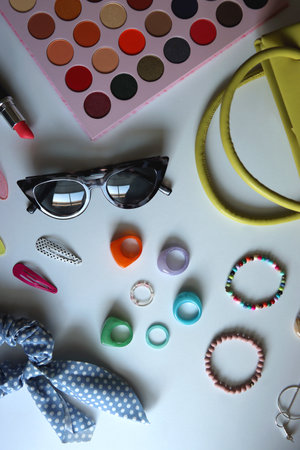 Green bag, various colorful jewelry, sunglasses, hair accessories and colorful make up on white background. Flat lay.の写真素材