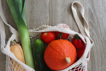 Mesh bag with various healthy vegetables on wooden background.の写真素材