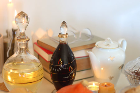 Lit candles, cookies, chocolate, nuts, tea, wine, pumpkins, books, reading glasses and autumn leaves on the table. Autumnal hygge at home. Selective focus.の写真素材