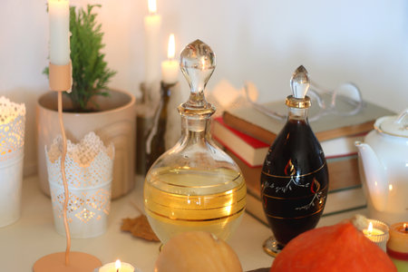 Lit candles, cookies, chocolate, nuts, tea, wine, pumpkins, books, reading glasses and autumn leaves on the table. Autumnal hygge at home. Selective focus.の写真素材