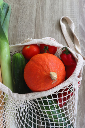 Mesh bag with various healthy vegetables on wooden background.の写真素材