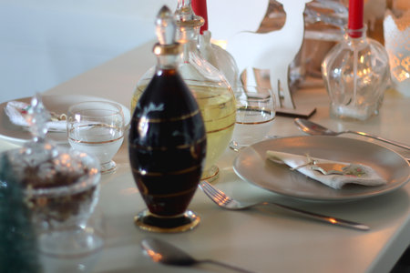 Table set for Christmas meal, with plates, wine, decorations and lit candles. Selective focus.の写真素材